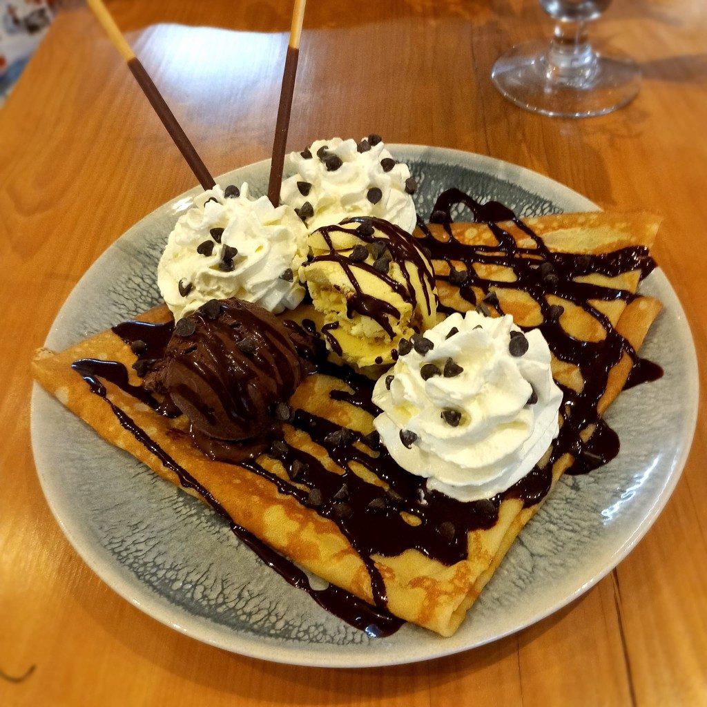 Une crêpe garnie de glace, de chantilly et de sauce chocolat