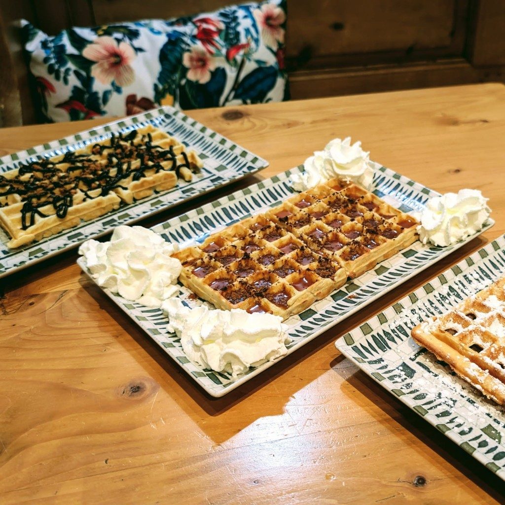 Des gaufres fines saupoudrées de sucre glace, sur un plat bleu et blanc