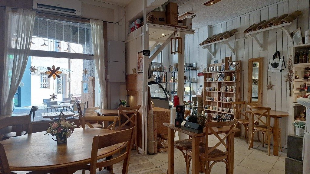 La salle du salon de thé : tables en bois, étagères de thés et d'épicerie fine, grandes fenêtres